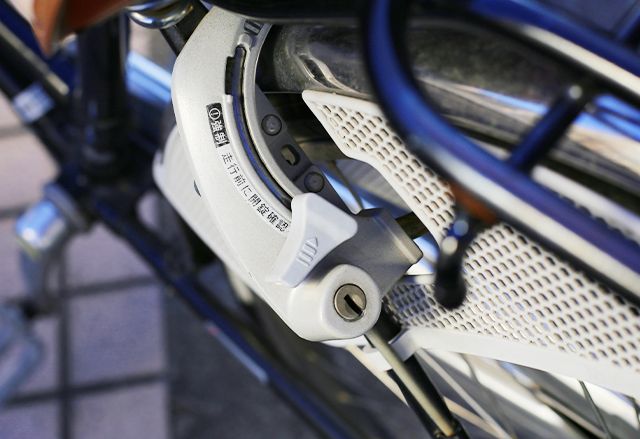 自転車の後輪に取り付けられた馬蹄錠を撮った写真。半円形の金具が車輪の間に入り、下に鍵穴がある