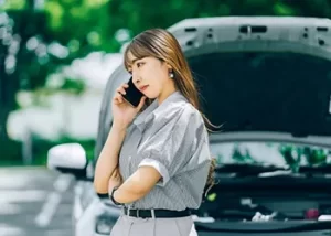 車の前で電話する女性